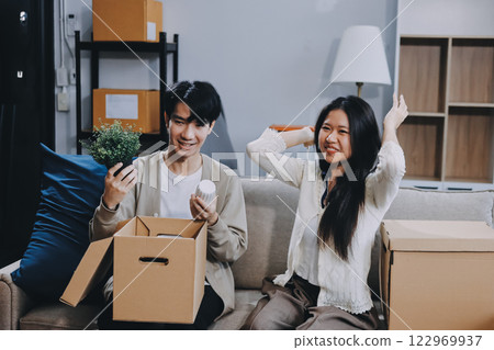 Smiling couple unpacking boxes in new house 122969937