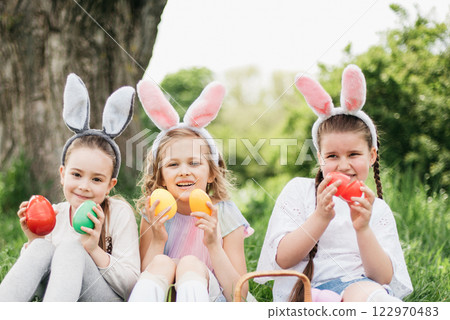 Easter egg hunt. Group Of Children Wearing Bunny Ears Running To Pick Up colorful Egg On Easter Egg Hunt In Garden. Easter tradition Easter egg hunt. Group Of Children Wearing Bunny Ears Running To Pick Up colorful Egg On Easter Egg Hunt In Garden. Easter tradition 122970483