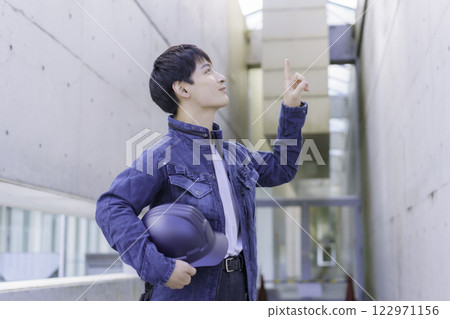 A young worker holding a helmet and inspecting the site 122971156