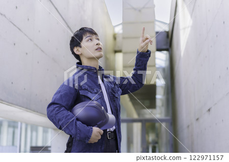 A young worker holding a helmet and inspecting the site 122971157
