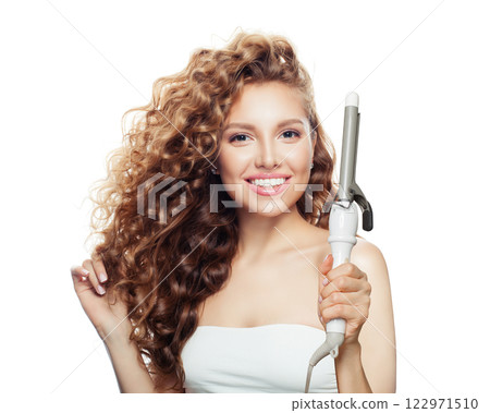 Isolated woman with curly hairstyle using hot curling tongs iron, indoor fashion portrait. 122971510