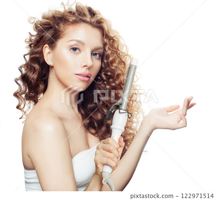 Fashionable woman with healthy long wavy hair  holding empty palm hand and using curlyng iron 122971514