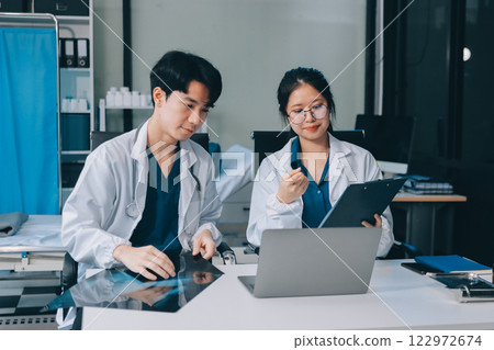 Positive doctor working on laptop in medical office, portrait. 122972674