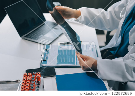 Positive doctor working on laptop in medical office, portrait. Positive doctor working on laptop in medical office, portrait. 122972699