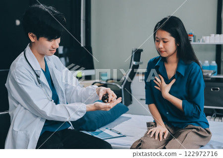 doctor consulting senior old patient filling form at consultation. Professional physician wearing white coat talking to mature woman signing medical paper at appointment visit in clinic. 122972716