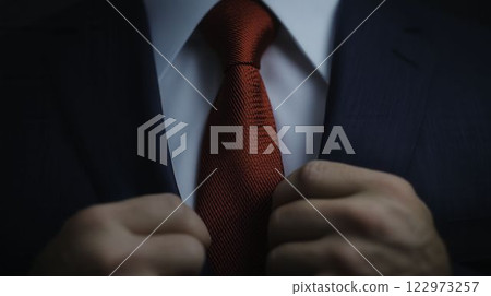 Man Adjusting Red Tie in Tailored Suit with Focus on Attire Man Adjusting Red Tie in Tailored Suit with Focus on Attire 122973257