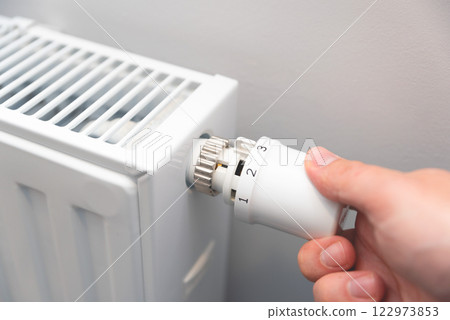 Modern white radiator, hand holding thermostat 122973853