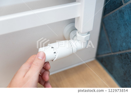 Modern white radiator, hand holding thermostat 122973854