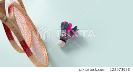 Two wooden badminton rackets and colorful feather badminton shuttlecock on blue background. View from above. Concept racket sport. Leisure games. 122973928