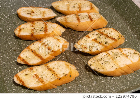 Several slices of seasoned and grilled bread on a speckled non-stick grill pan 122974790