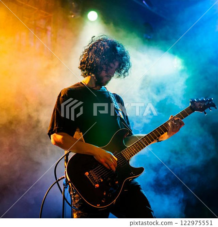 Silhouette of a guitarist playing passionately on a live stage Silhouette of a guitarist playing passionately on a live stage 122975551