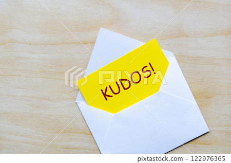 KUDOS text on yellow notepad inside an envelope. Achievement concept. KUDOS text on yellow notepad inside an envelope. Achievement concept. 122976365