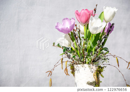 A vibrant arrangement of tulips in various colors stands in a decorative vase, enhancing the spring atmosphere 122976656