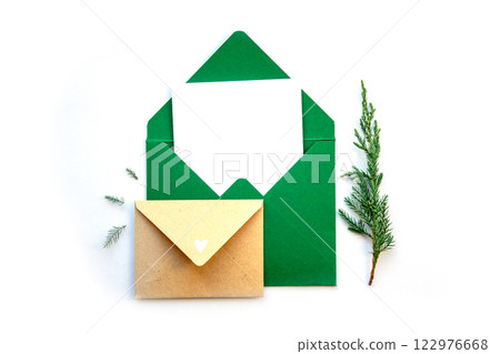 Colorful green envelopes with a blank card and a small brown envelope beside pine sprigs on a white background Colorful green envelopes with a blank card and a small brown envelope beside pine sprigs on a white background 122976668