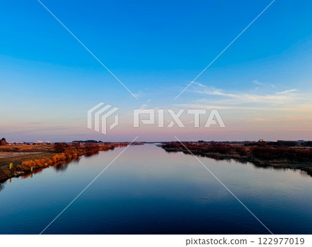 一條河流兩岸鋪滿了秋葉,暮色中的天空倒映在平靜的水面上。 一條河流兩岸鋪滿了秋葉,暮色中的天空倒映在平靜的水面上。 122977019
