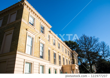 A historic brick building bathed in bright sunlight under a clear blue sky at Kew Gardens in the outskirts of London 122977207