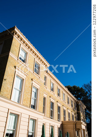 A historic brick building bathed in bright sunlight under a clear blue sky at Kew Gardens in the outskirts of London 122977208
