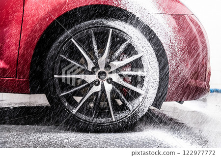 Red car and wheel covered in thick active foam for a deep, thorough wash 122977772