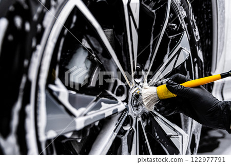 car wash or detailing studio employee cleans rims with a detailing brush  122977791