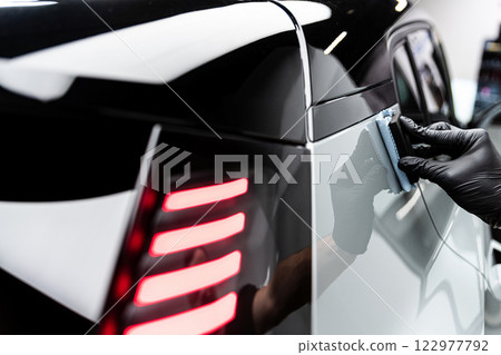 Car wash or detailing studio employee applies ceramic or graphene coating on gray paint Car wash or detailing studio employee applies ceramic or graphene coating on gray paint 122977792