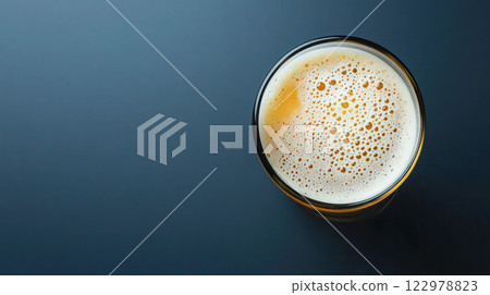 Top view of a frothy beer glass on a dark blue background, ideal for beverage advertising or bar promotions, copy space. 122978823