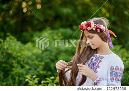 Girl in traditional ukrainian wreath on head blue and yellow flag of Ukraine in field. Ukraine's Independence Flag Day. Constitution day. 24 August. Patriotic holiday. Girl in traditional ukrainian wreath on head blue and yellow flag of Ukraine in field. Ukraine's Independence Flag Day. Constitution day. 24 August. Patriotic holiday. 122978966