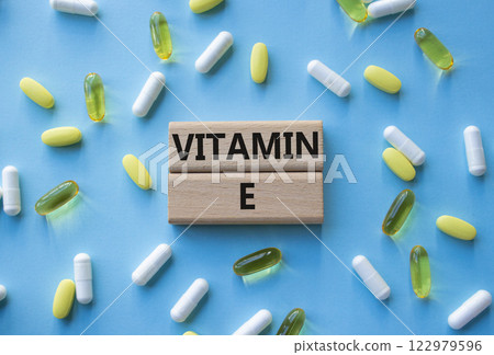 Vitamin E symbol. Concept word Vitamin E on wooden blocks. Beautiful pink background with pills. Medicine and Vitamin E concept. Copy space 122979596