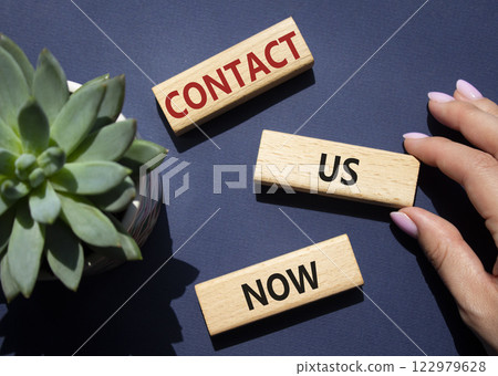 Contact us now symbol. Wooden blocks with words Contact us now. Beautiful deep blue background with succulent plant. Businessman hand. Business and Contact us now concept. Copy space. 122979628