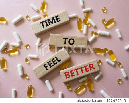 Time to feel better symbol. Concept word Time to feel better on wooden blocks. Beautiful pink background with pills. Health concept. Copy space 122979643