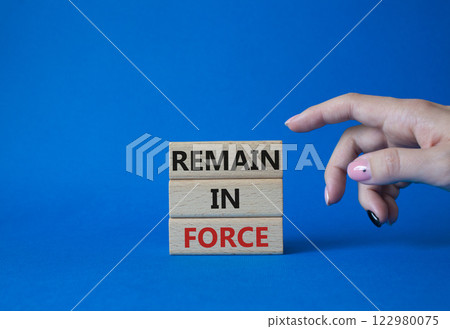 Remain in Force symbol. Concept words Remain in Force on wooden blocks. Businessman hand. Beautiful blue background. Business and Remain in Force concept. Copy space 122980075