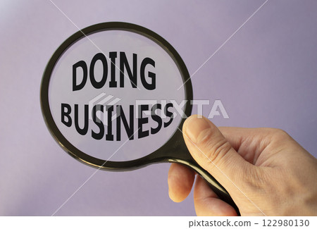 Doing Business symbol. Magnifying Glass with Concept word Doing Business. Businessman hand. Beautiful purple background. Business and Doing Business concept. Copy space 122980130