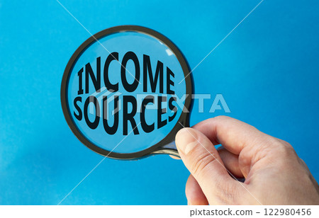 Income Sources symbol. Magnifying Glass with Concept word Income Sources. Beautiful blue background. Businessman hand. Business and Income Sources concept. Copy space Income Sources symbol. Magnifying Glass with Concept word Income Sources. Beautiful blue background. Businessman hand. Business and Income Sources concept. Copy space 122980456