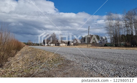 Sunny early spring day. gray asvaled road, blue sky, white clouds. 122980517