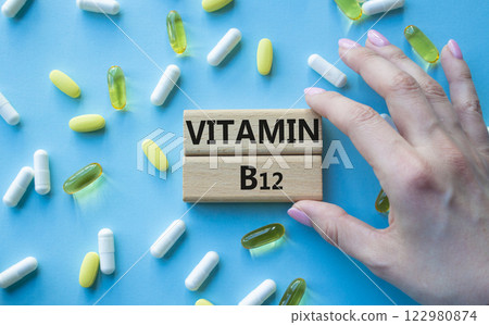 Vitamin B12 symbol. Concept word Vitamin B12 on wooden blocks. Beautiful blue background with pills. Doctor Hand. Medicine and Vitamin B12 concept. Copy space 122980874