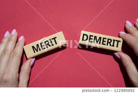 Merit or Demerit symbol. Concept word Merit or Demerit on wooden blocks. Businessman hand. Beautiful red background. Business and Merit or Demerit concept. Copy space 122980892
