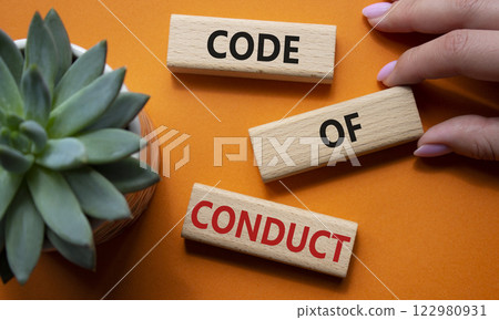 Code of conduct symbol. Wooden blocks with words Code of conduct. Businessman hand. Beautiful orange background with succulent plant. Business and Code of conduct concept. Copy space. Code of conduct symbol. Wooden blocks with words Code of conduct. Businessman hand. Beautiful orange background with succulent plant. Business and Code of conduct concept. Copy space. 122980931