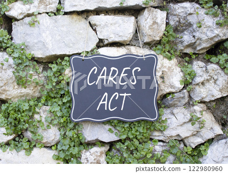 Cares Act symbol. Stone wall with words Cares Act. Beautiful stone background with plants. Business and Cares Act concept. Copy space. 122980960