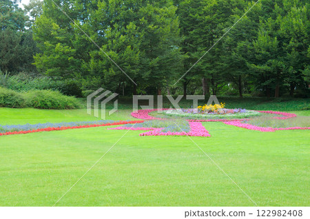 A beautiful garden with a bright flower bed and a green meadow. A beautiful garden with a bright flower bed and a green meadow. 122982408