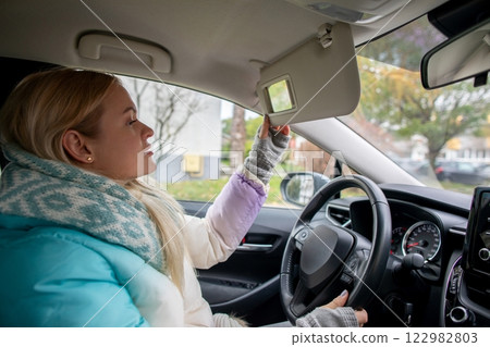 A Young Woman is Adjusting the Sun Visor in her Car while Enjoying the Daylight Hours A Young Woman is Adjusting the Sun Visor in her Car while Enjoying the Daylight Hours 122982803
