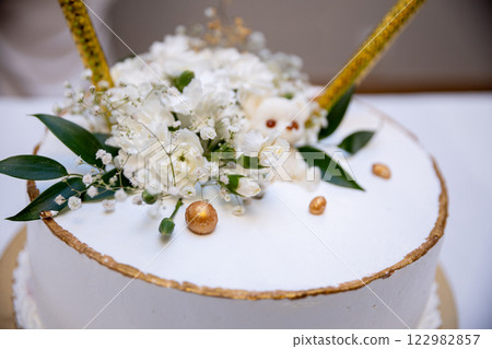 An Elegant Wedding Cake Featuring Stunning Floral Decoration and Beautiful Golden Accents An Elegant Wedding Cake Featuring Stunning Floral Decoration and Beautiful Golden Accents 122982857