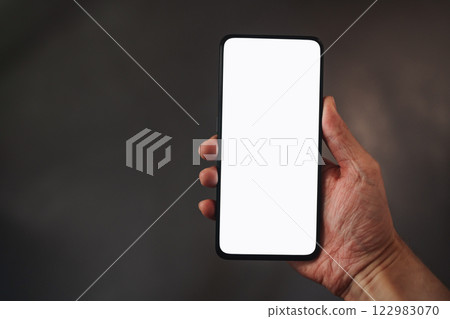 Man hold smartphone with white screen in his hand standing indoors in home environment Man hold smartphone with white screen in his hand standing indoors in home environment 122983070