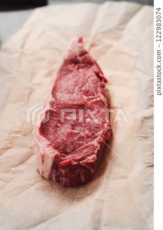 Raw new york sirloin steak on parchment paper warming up before cooking Raw new york sirloin steak on parchment paper warming up before cooking 122983074