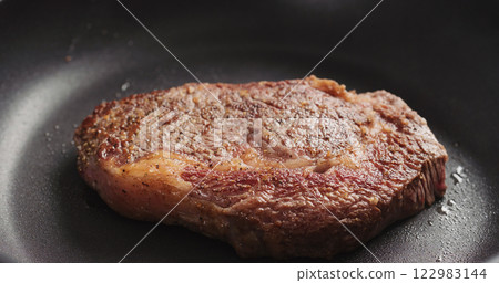 Closeup shot of ribeye steak frying on non stick pan Closeup shot of ribeye steak frying on non stick pan 122983144