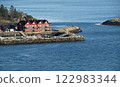 Traditional red wooden house by the rocky shore 122983344