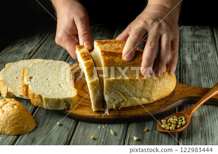 Freshly baked bread is sliced with care, revealing its soft texture on a rustic wooden board Freshly baked bread is sliced with care, revealing its soft texture on a rustic wooden board 122983444
