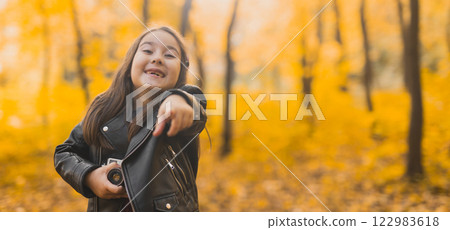Banner surprised child girl using an old-fashioned camera in autumn nature. Photographer, fall season and emotions concept. Copy space 122983618