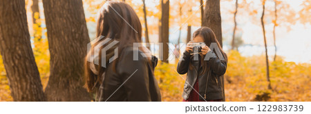Banner Child taking picture her mother on retro camera in autumn park. Hobbies and leisure concept. Copy space 122983739