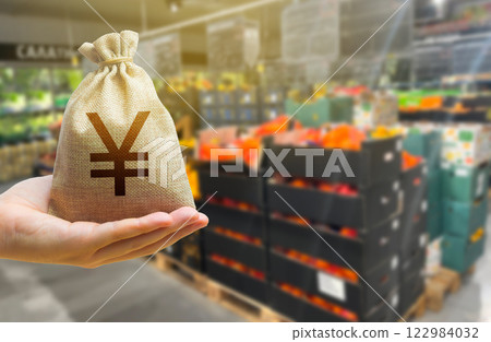 Concept of cost of goods and food products. Grocery set. Import and export. Japanese yen money bag on the background of a grocery store counter with fresh organic vegetables and fruits. 122984032