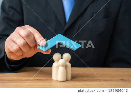 Property and family insurance concept. Miniature figures of a family stands under blue roof. Real estate and insurance agent services 122984042