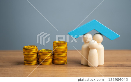 Property, home or health insurance concept. Family figurine under blue roof and coins 122984043